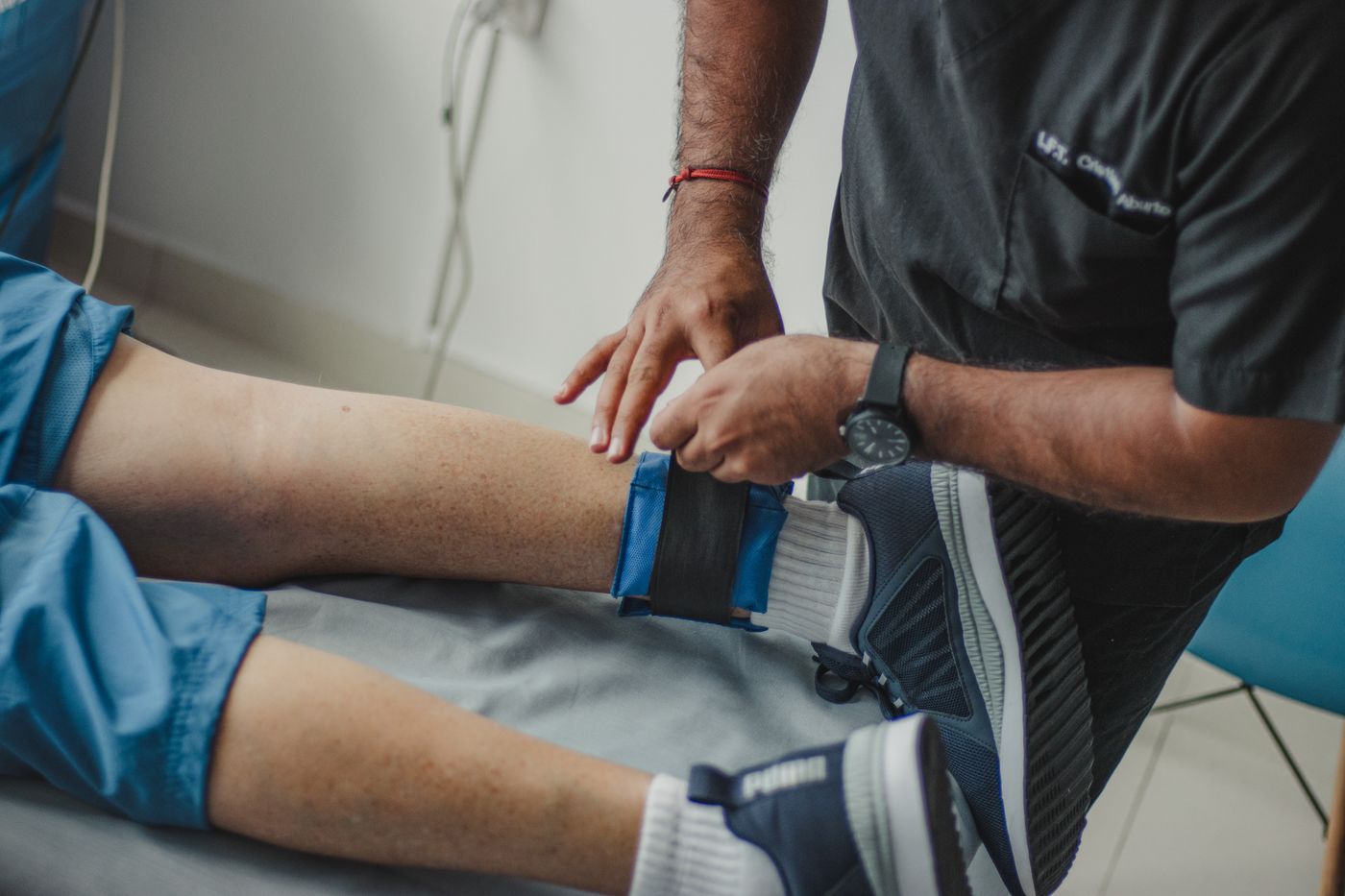 A physiotherapist adjusting a support on a patient's leg in a clinic
